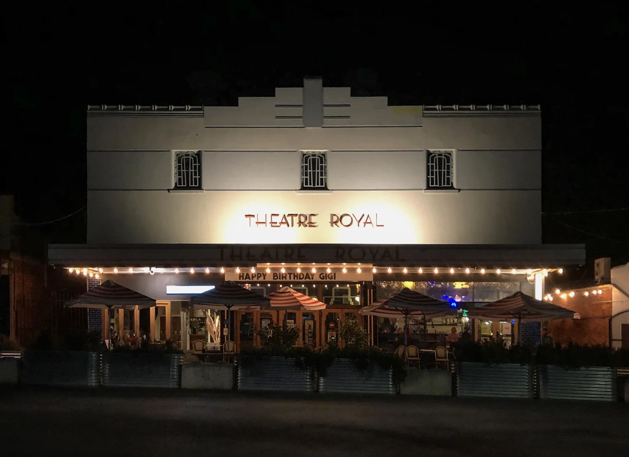 The art deco frontage of the Theatre Royal in Castlemaine at dusk, strung with lights over its footpath tables.